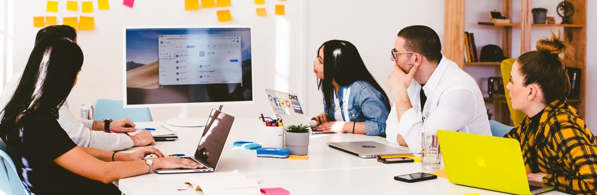 A team meeting around a table with a web page on a large monitor
